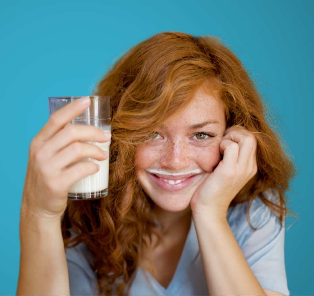 Eine Frau trinkt lächelnd ein Glas Milch, weil sie Milchprodukte wieder unbeschwert genießen kann.